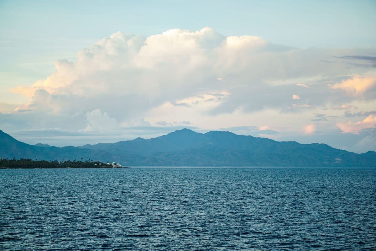 A coastal destination — sea, mountains, and open sky at dusk