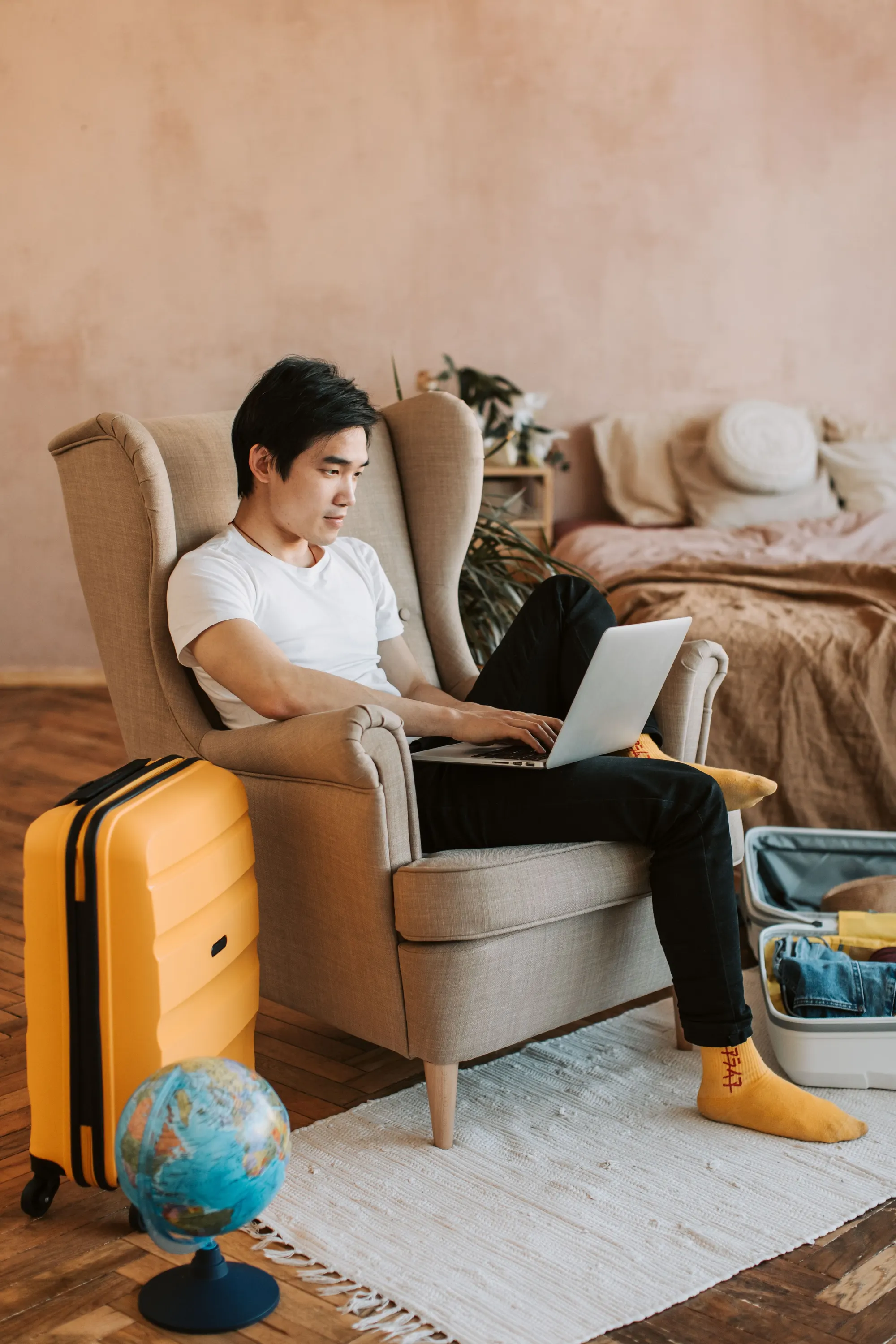 A traveler booking a stay online beside packed luggage